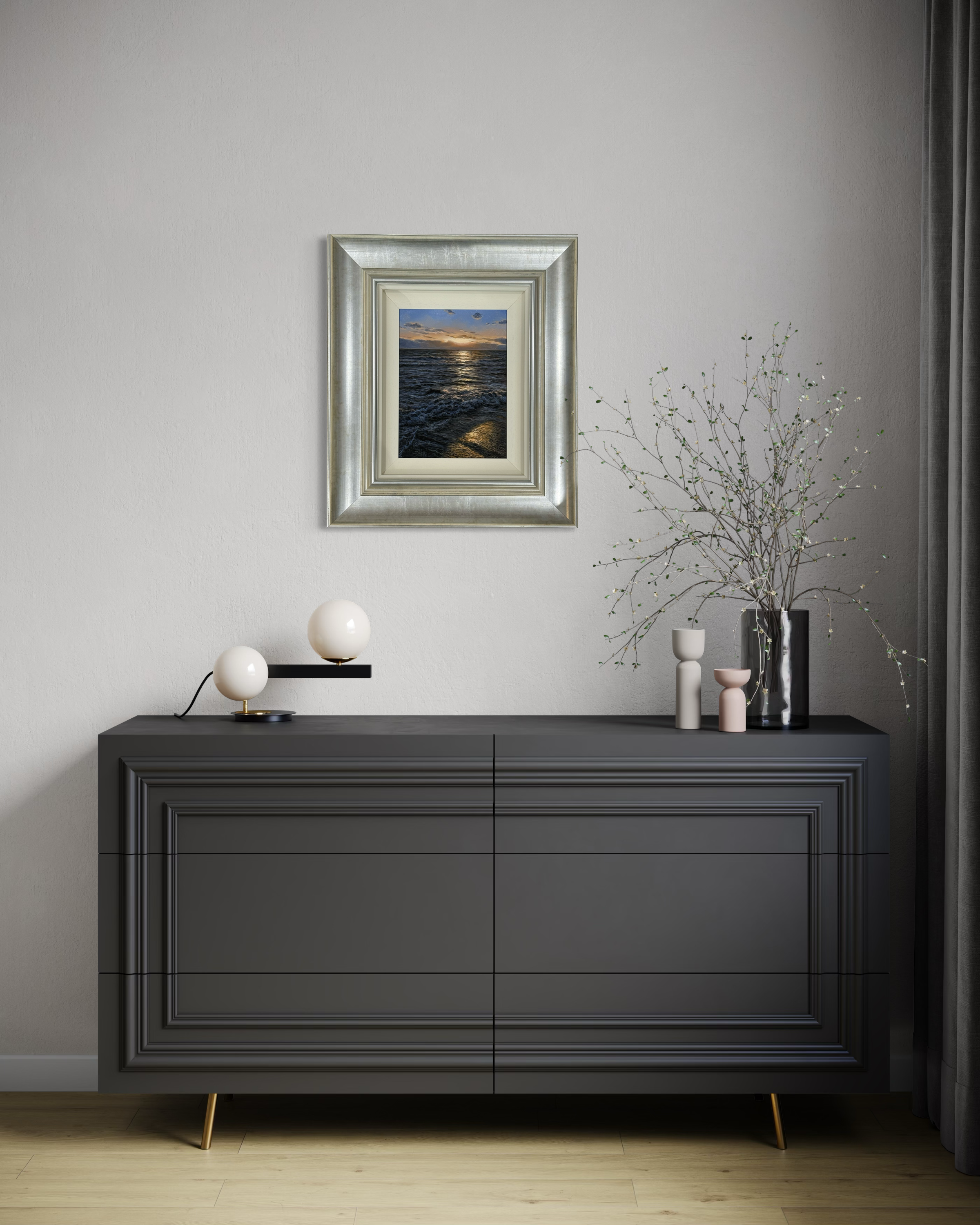 Modern interior with a dark gray dresser, framed artwork, and decorative items.