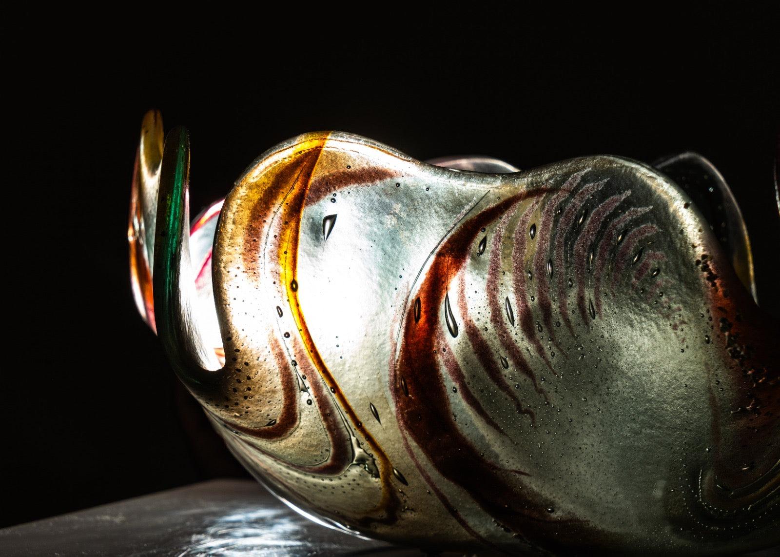 Close-up of a glass bowl with multicolored swirls on a black background