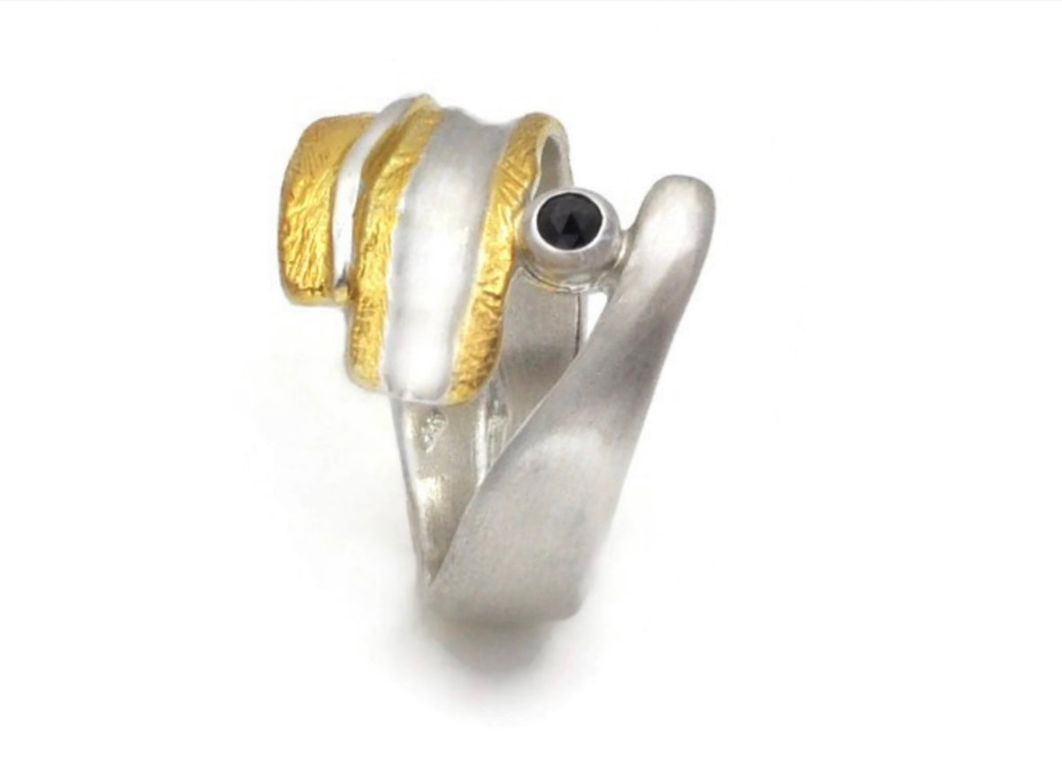 Silver and gold ring with a black gemstone on a white background