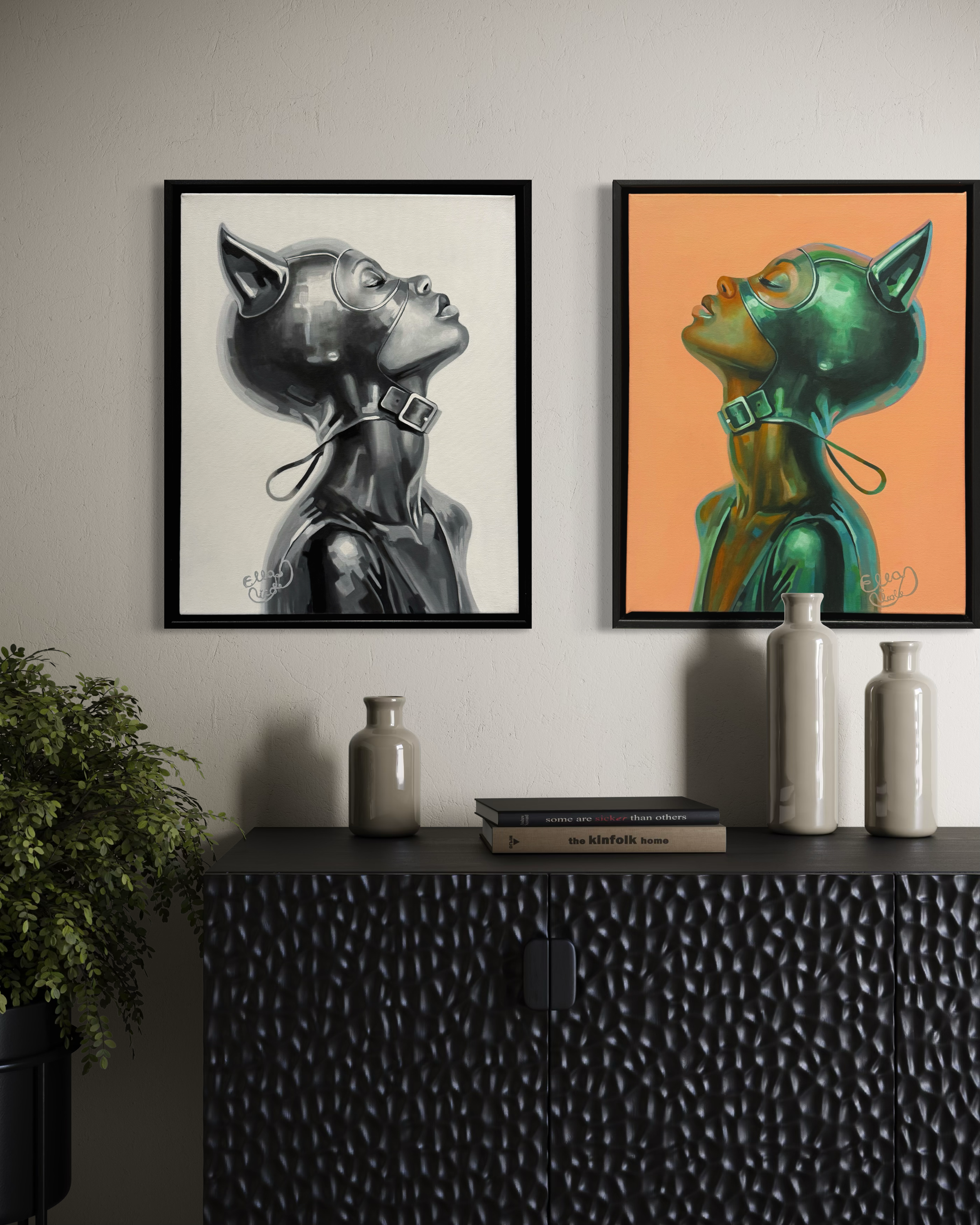 Two framed artworks of stylized figures on a wall above a black textured cabinet.