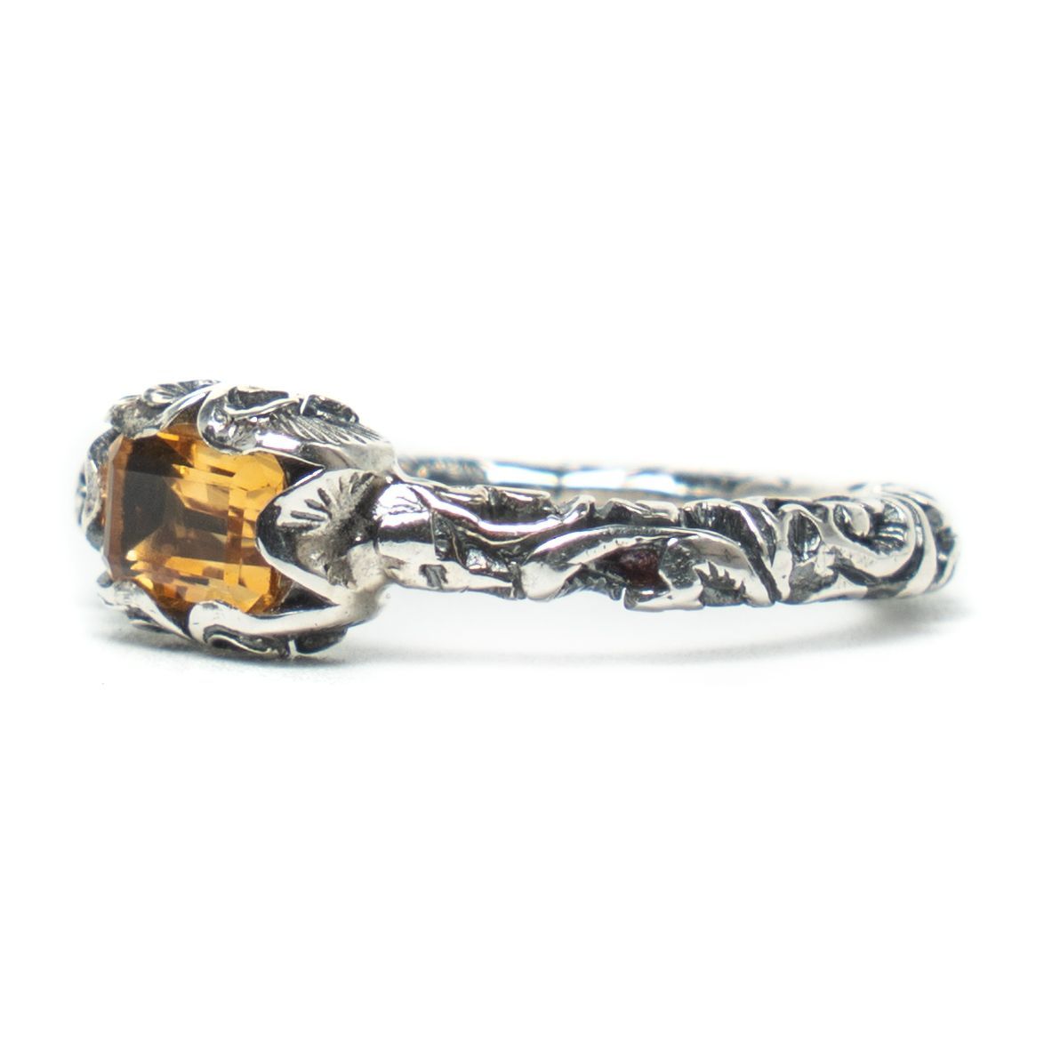 Silver ring with a yellow gemstone on a white background