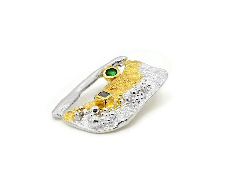 Gold and silver ring with green gemstone on a white background