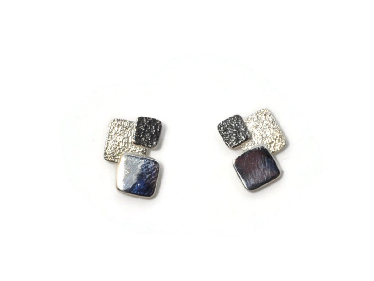 Pair of square-shaped earrings with metallic and dark stone components on a white background