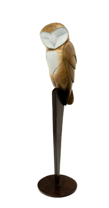 bronze owl figurine on a stand against a white background