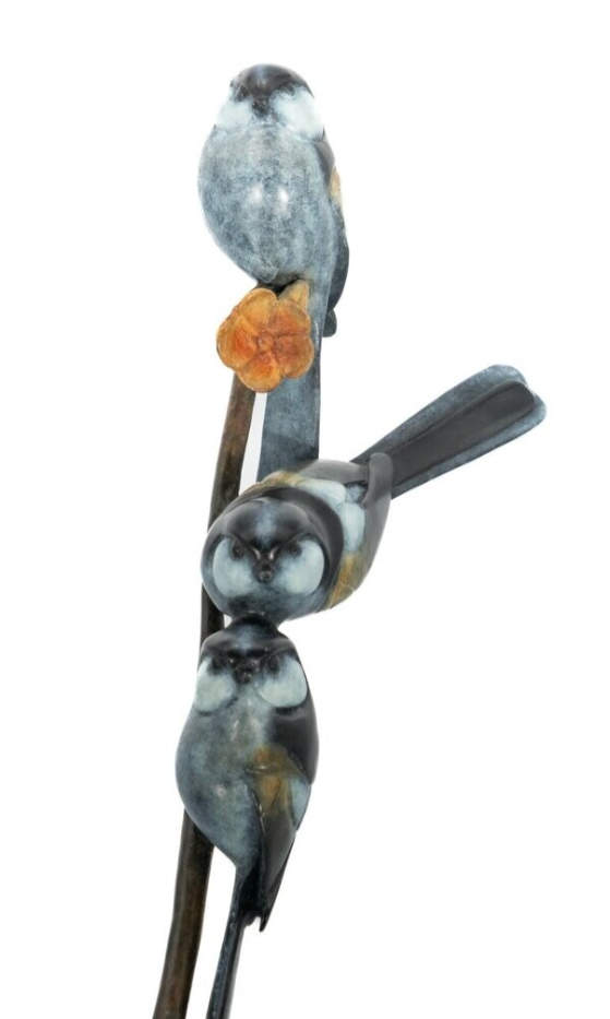 Three toy birds perched on a stick against a white background