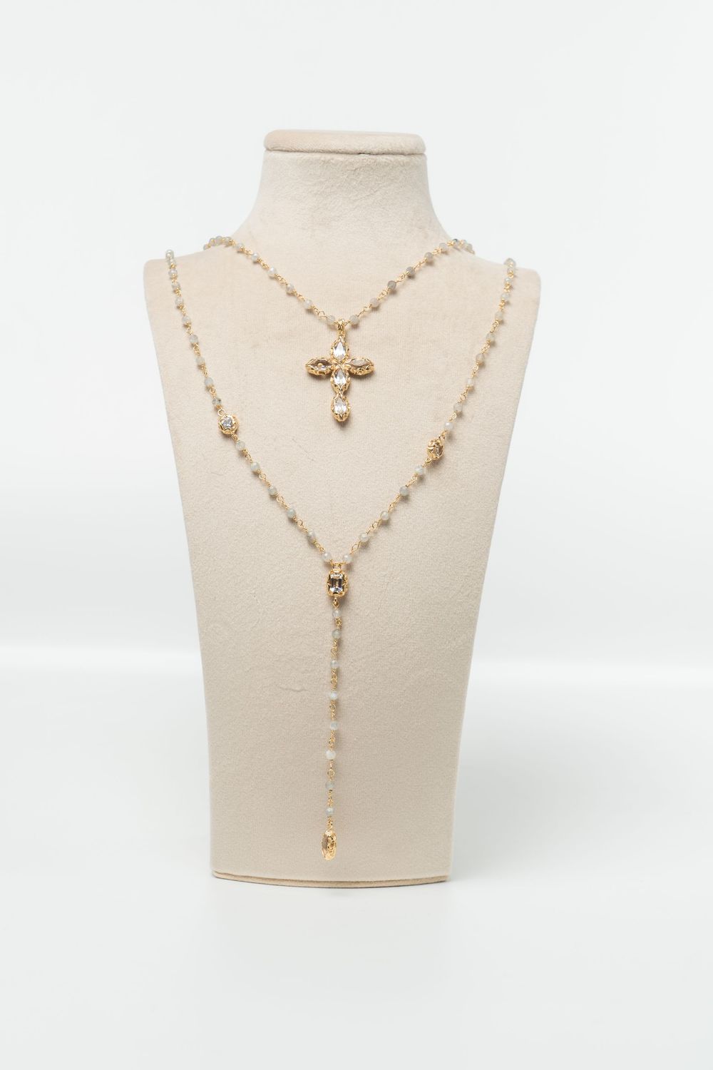 Gold necklace with a cross pendant on a mannequin bust against a white background