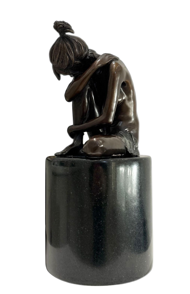 Bronze sculpture of a woman sitting on a pedestal against a white background