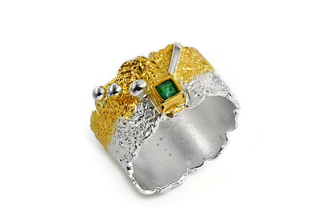Gold and silver ring with a green gemstone on a white background
