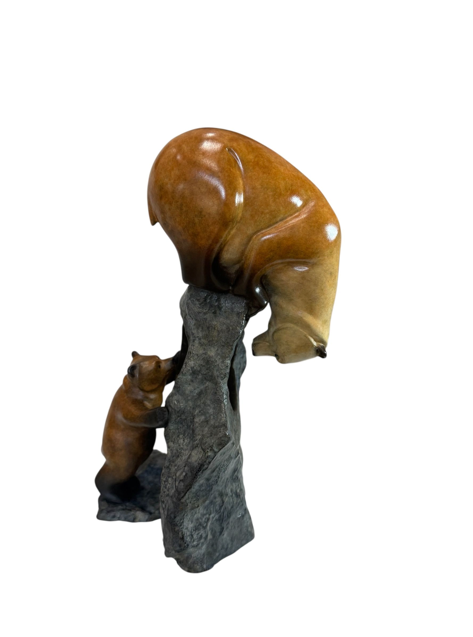 Statue of a bear climbing a rock with a large brown bear above on a white background