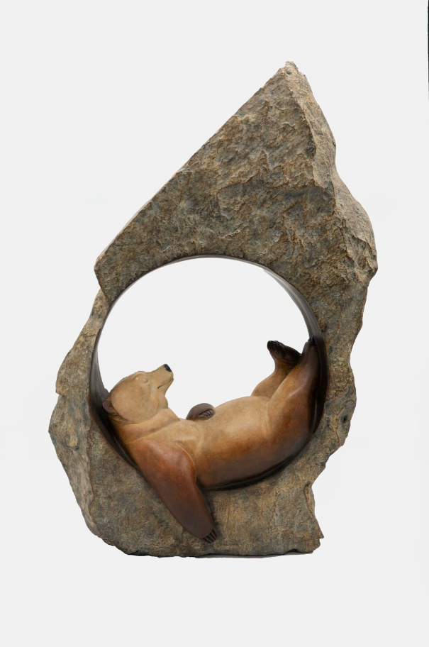 Statue of a bear lying inside a rock formation on a white background
