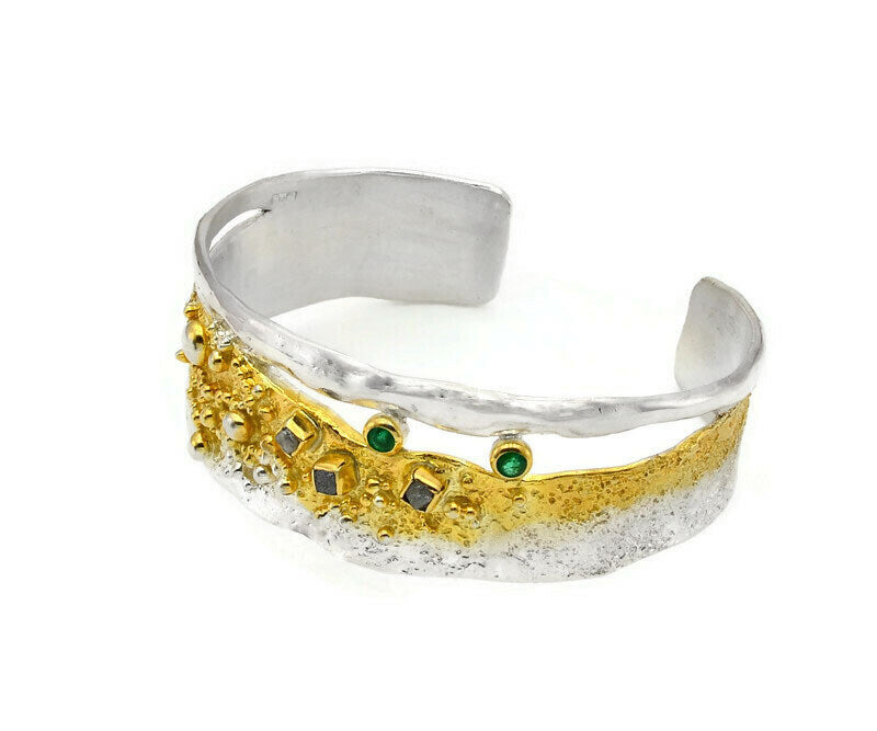 Silver and gold ring with embedded stones on a white background