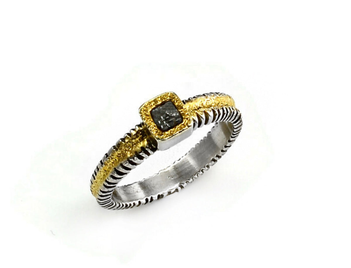 A two-tone ring featuring a textured silver band with a gold-painted top section, a square bezel-set black gemstone, and a matching textured gold bezel, shown on a white background.