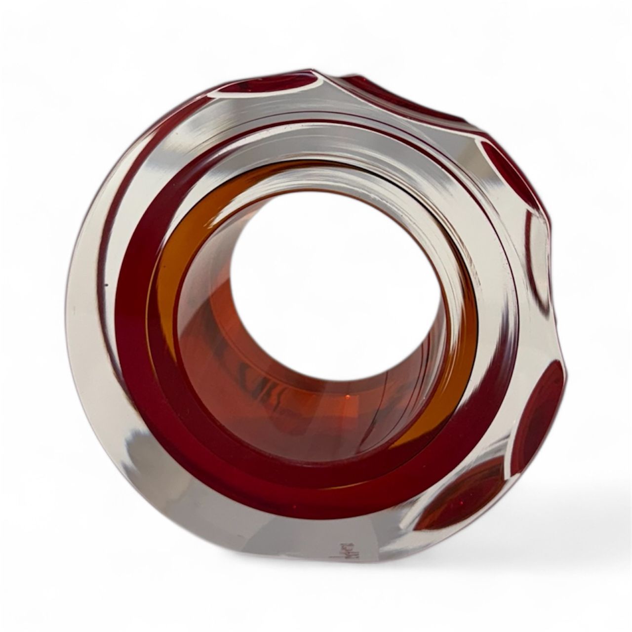 Decorative glass object with red and clear patterns on a white background