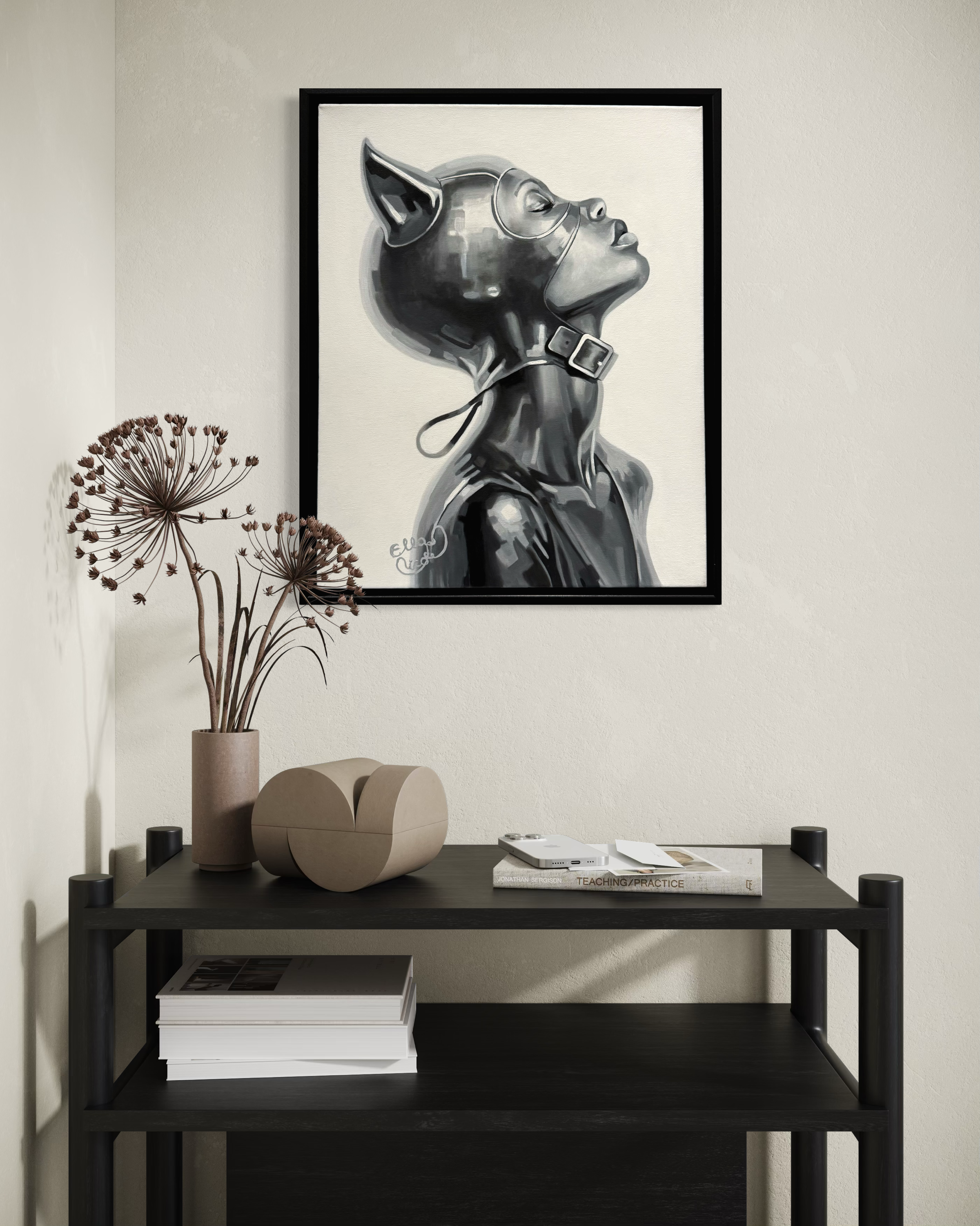 Framed artwork of a cat-like figure on a wall above a black shelf with decorative items.