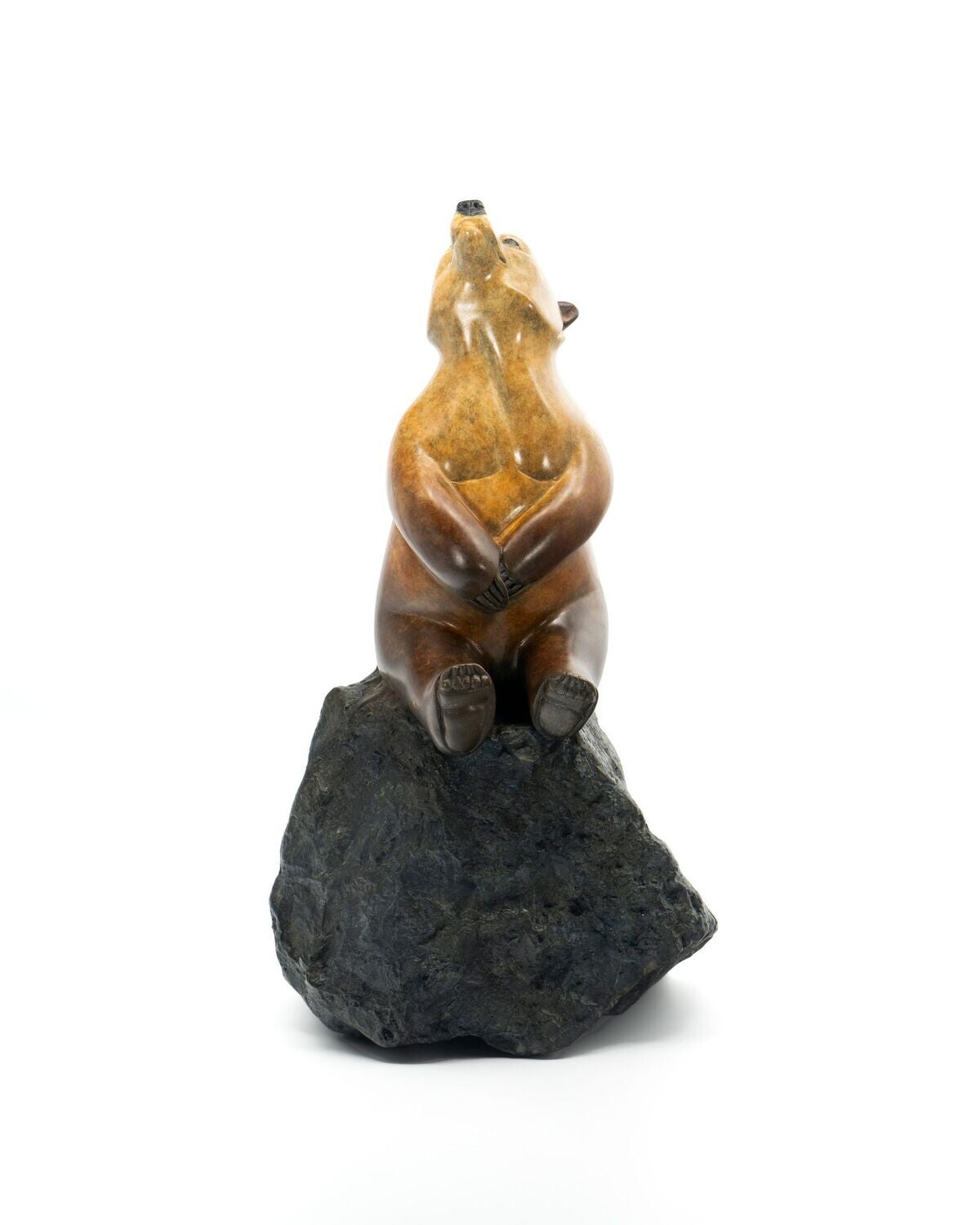 Carved stone bear figurine on a rock with a white background