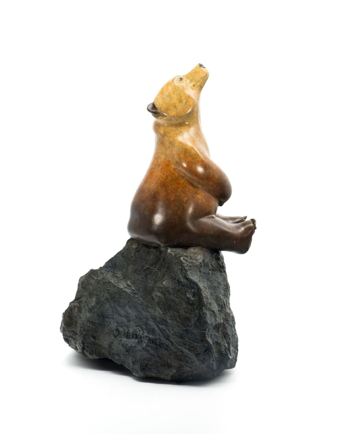 Brown bear figurine sitting on a rock against a white background