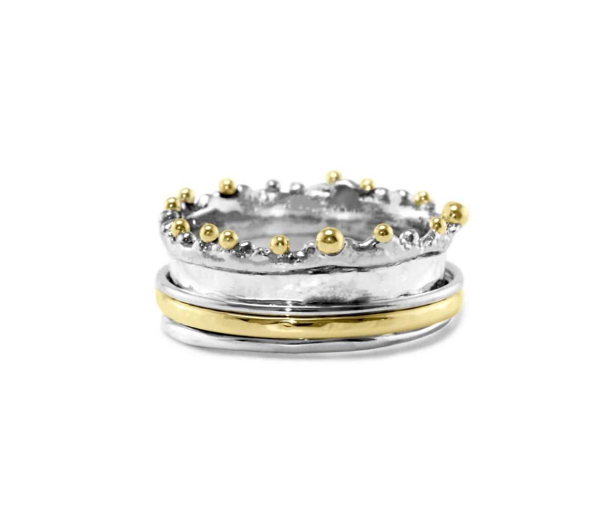Two stacked rings, one gold and one silver with gold beads, on a white background