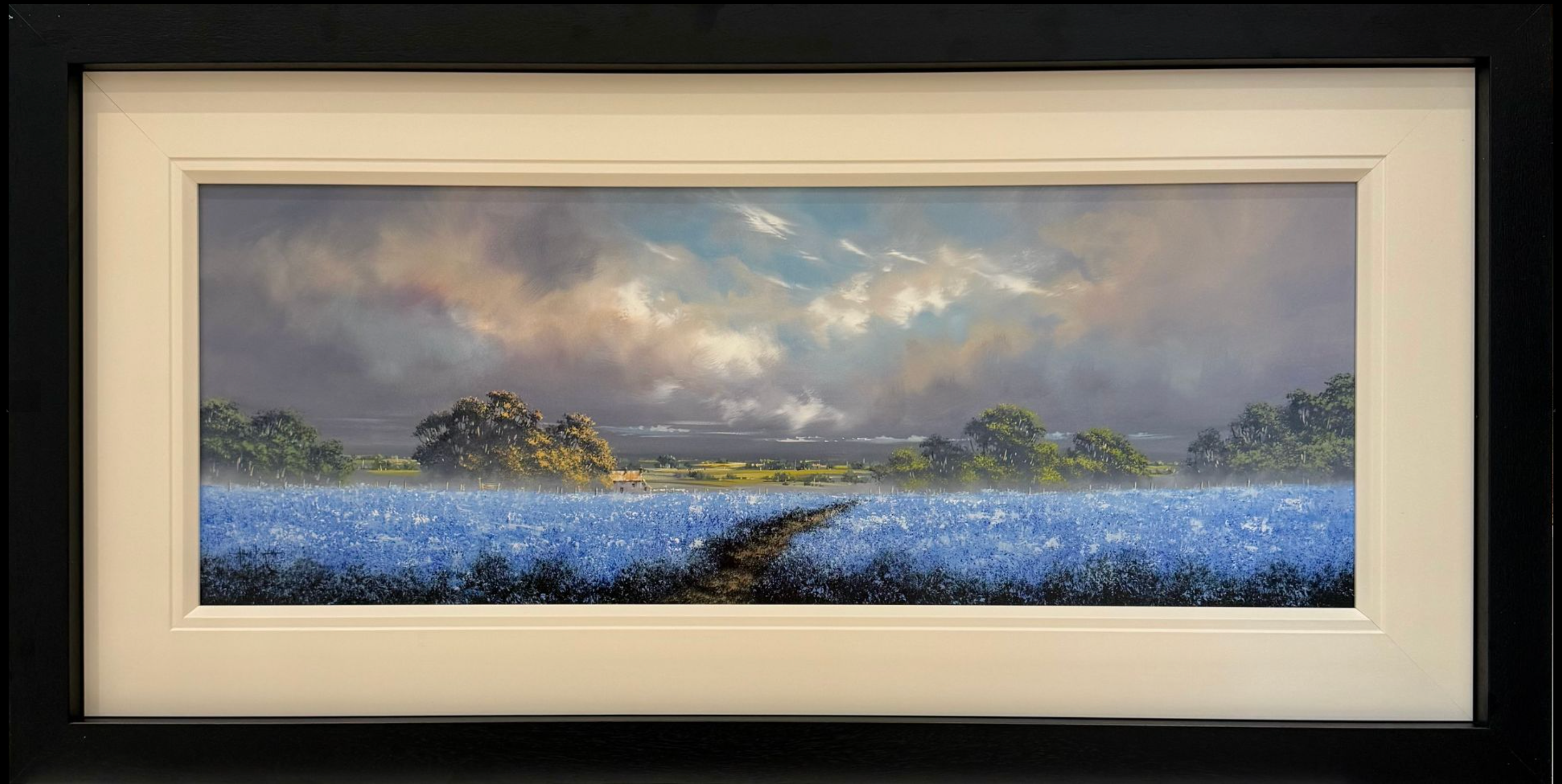 Framed artwork of a landscape with a path and blue flowers under a cloudy sky.