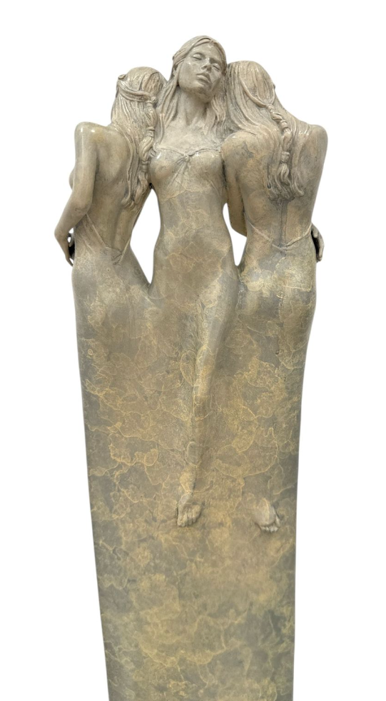 Bronze sculpture of three women in a flowing pose on a white background