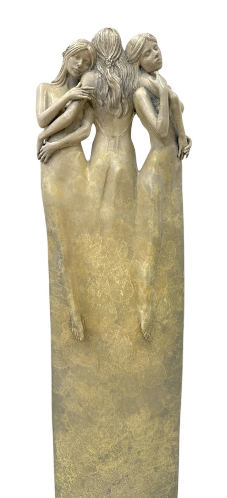 Bronze sculpture of three women in a close embrace on a white background