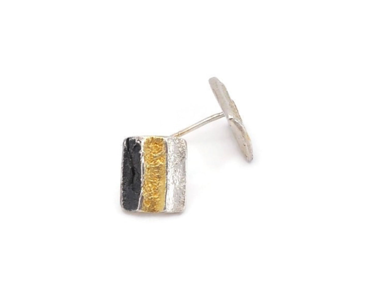 Silver earring with black and gold stripes on a white background