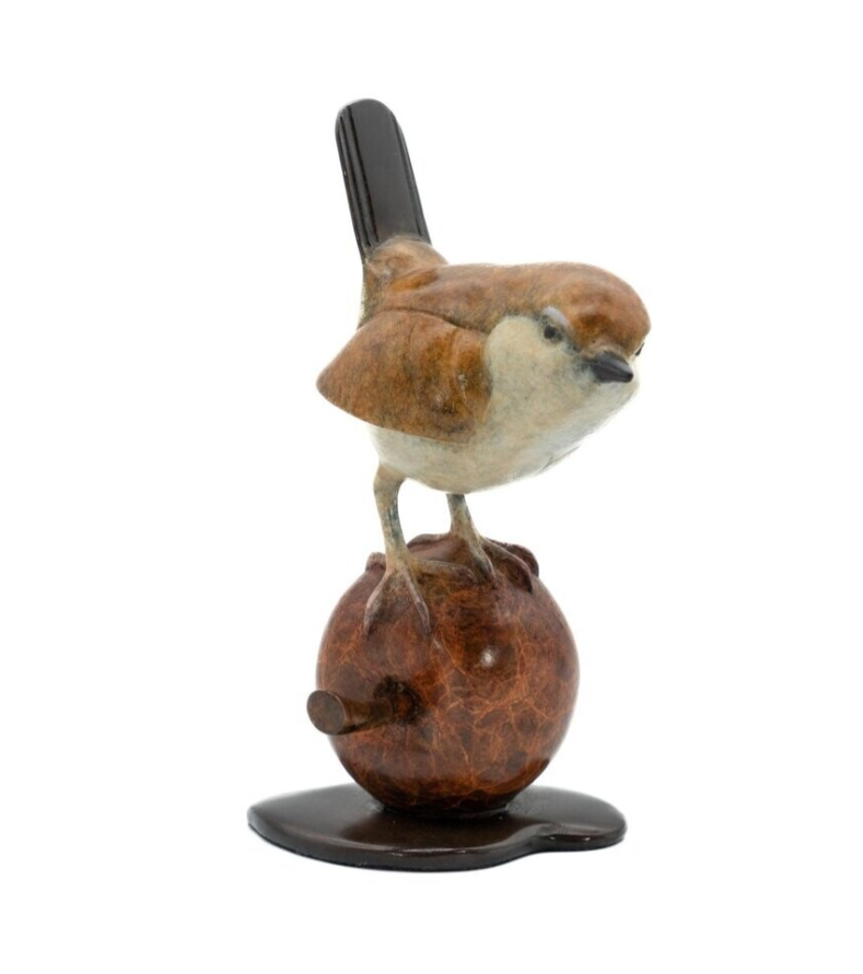 Bird figurine perched on a an apple against a white background