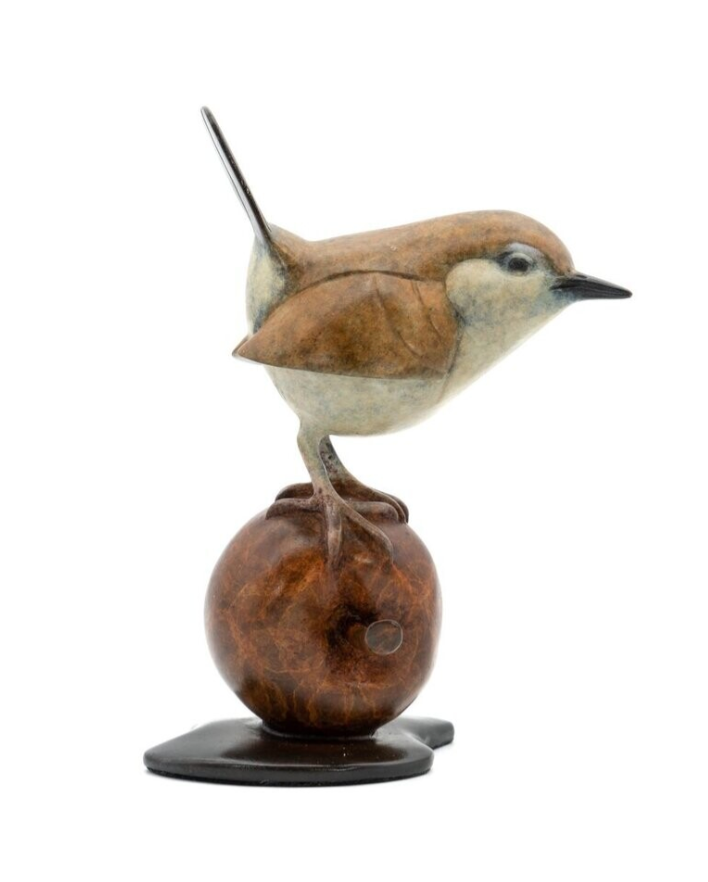 Bird figurine perched on an apple against a white background