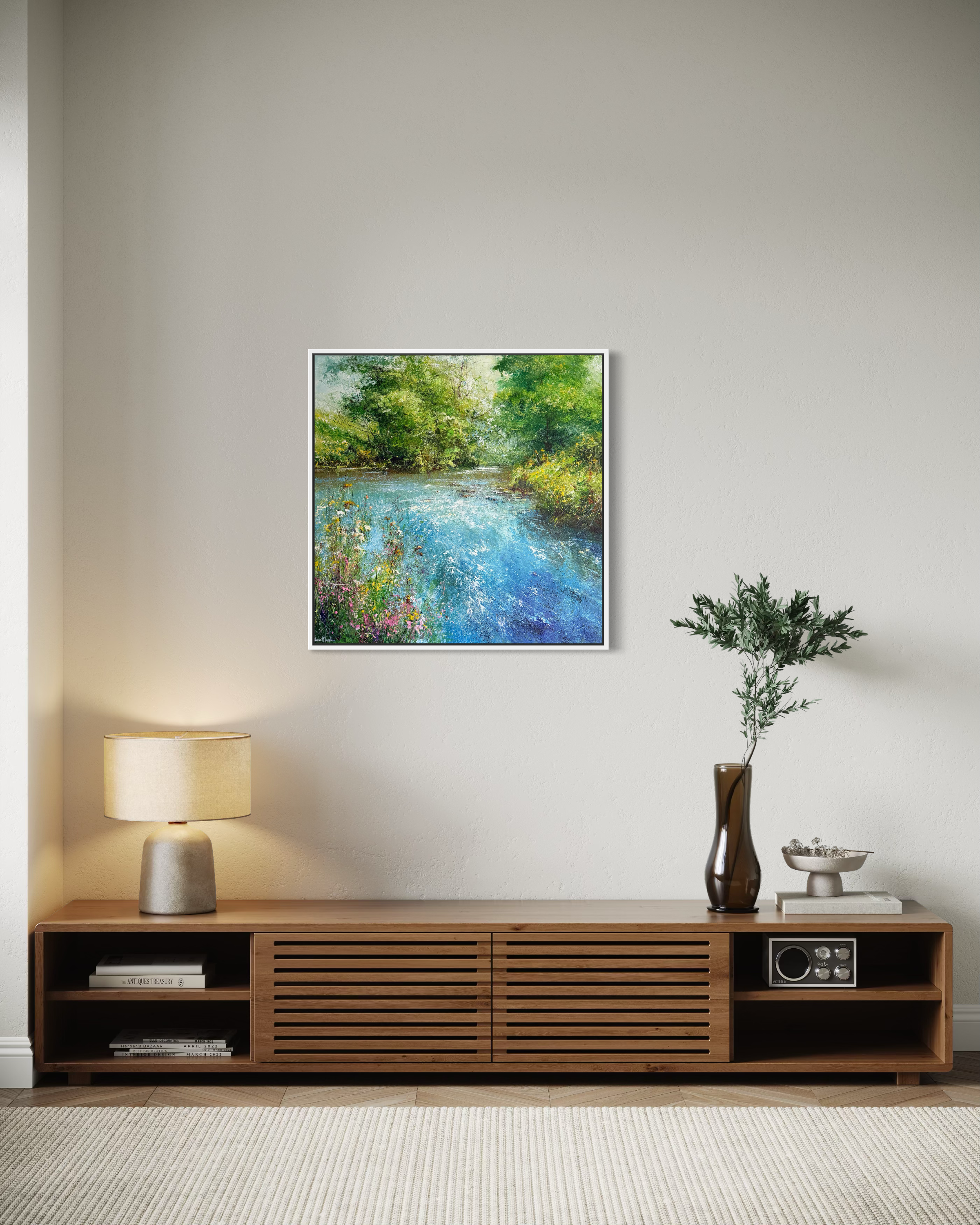 Framed painting of a river scene above a wooden console table in a room.