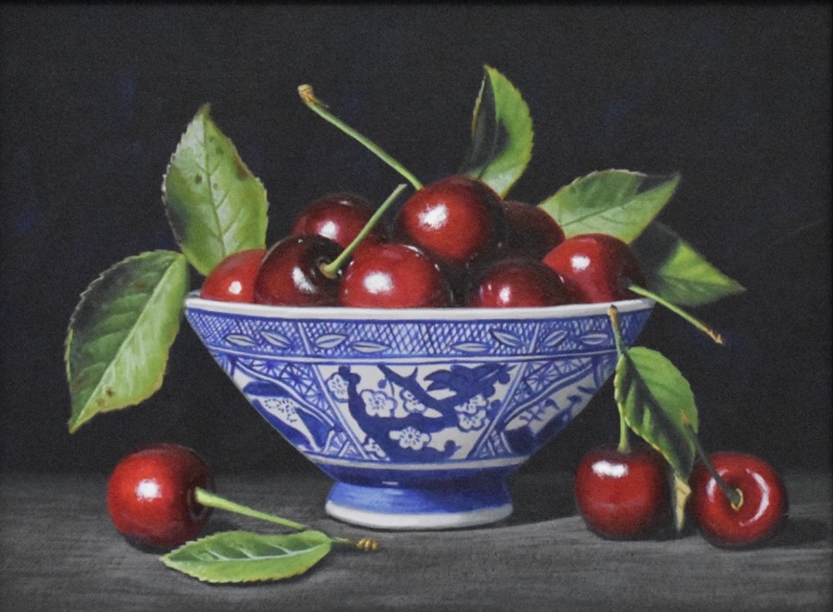 Still life painting of cherries in a blue and white bowl on a dark background