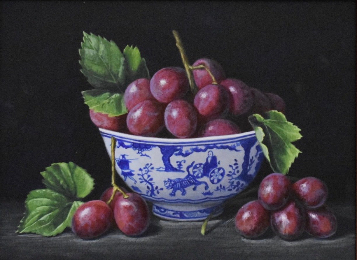 Still life painting of a blue and white bowl with red grapes on a dark background