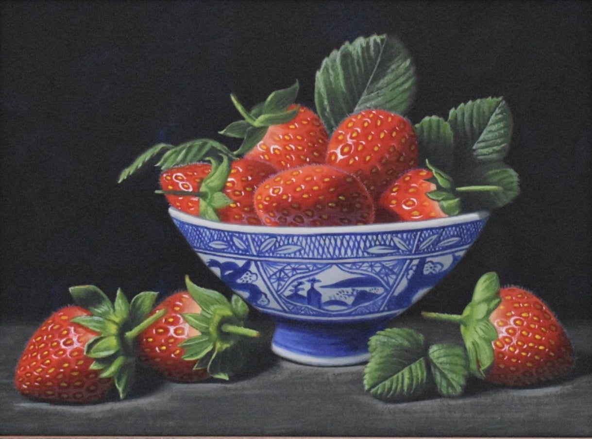 Bowl of strawberries with a blue and white pattern on a dark background