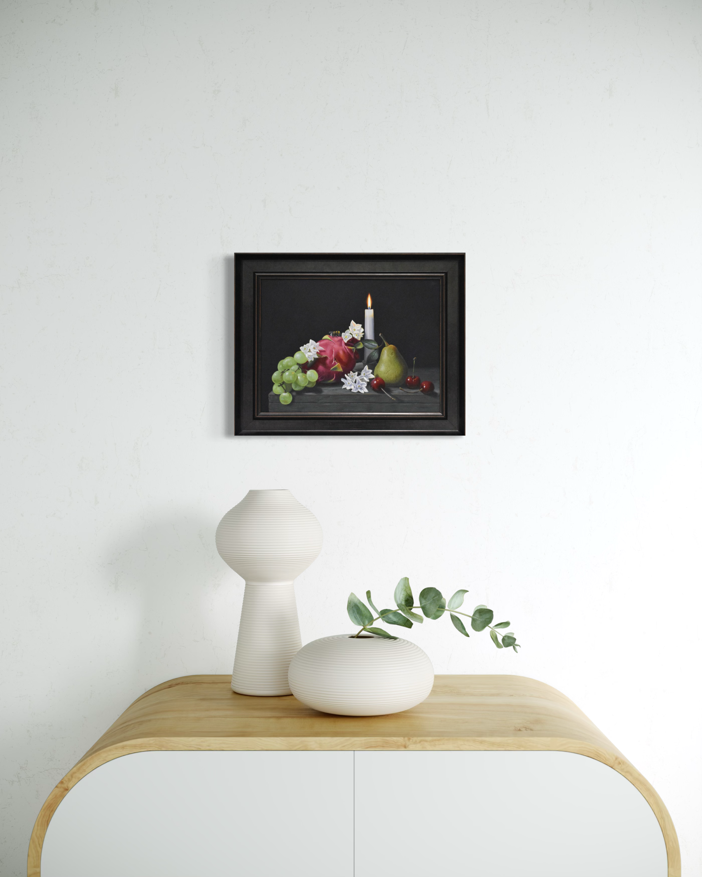 Framed still life artwork above a wooden side table with decorative items.