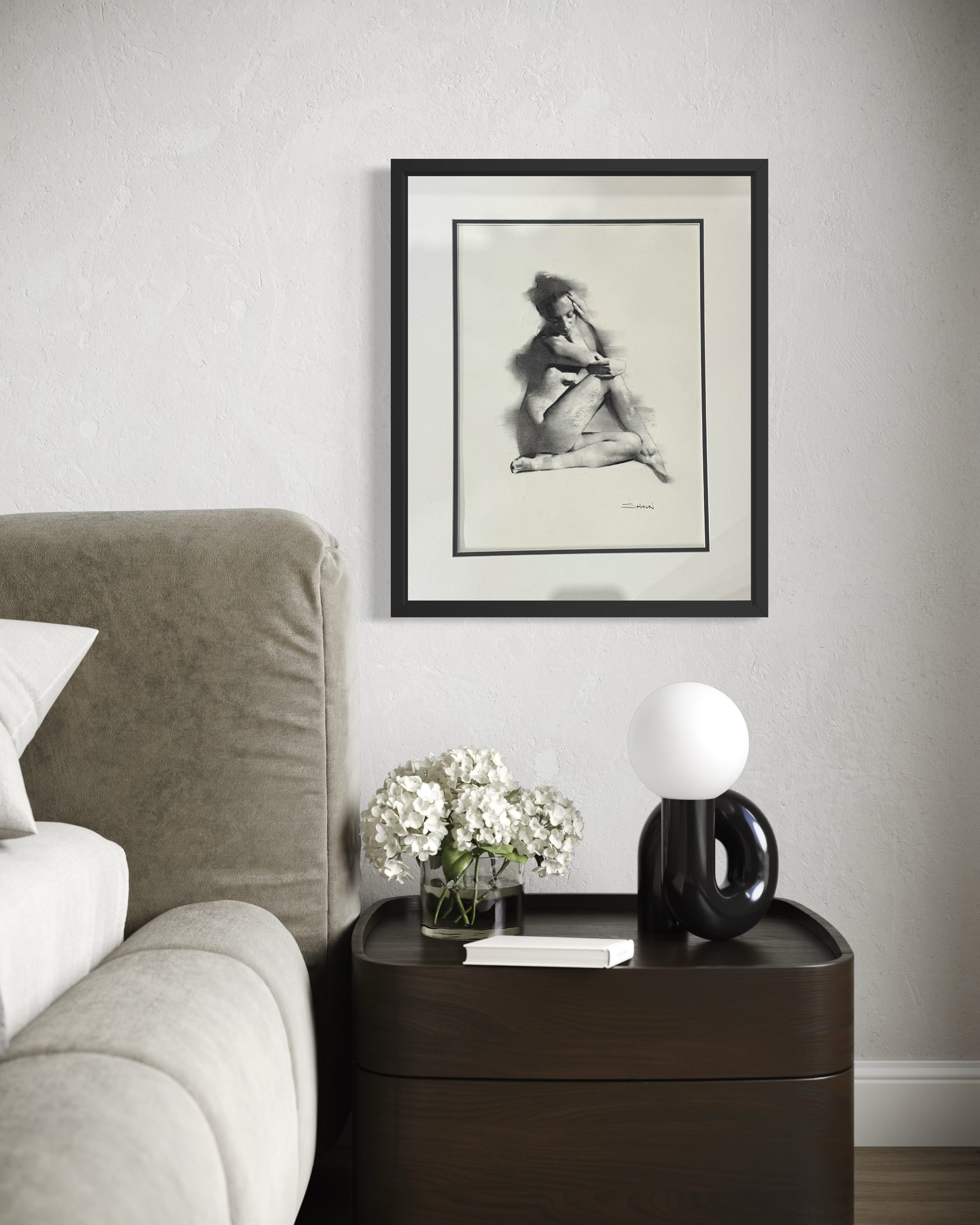 Framed artwork above a nightstand with decorative items in a bedroom setting
