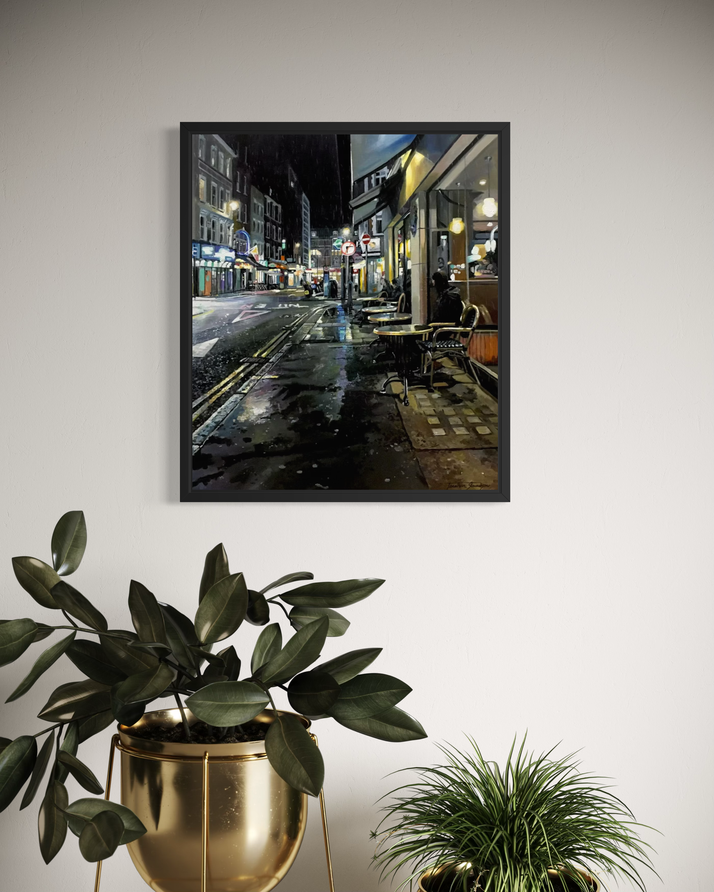 Framed london city street at night print on a wall with plants below