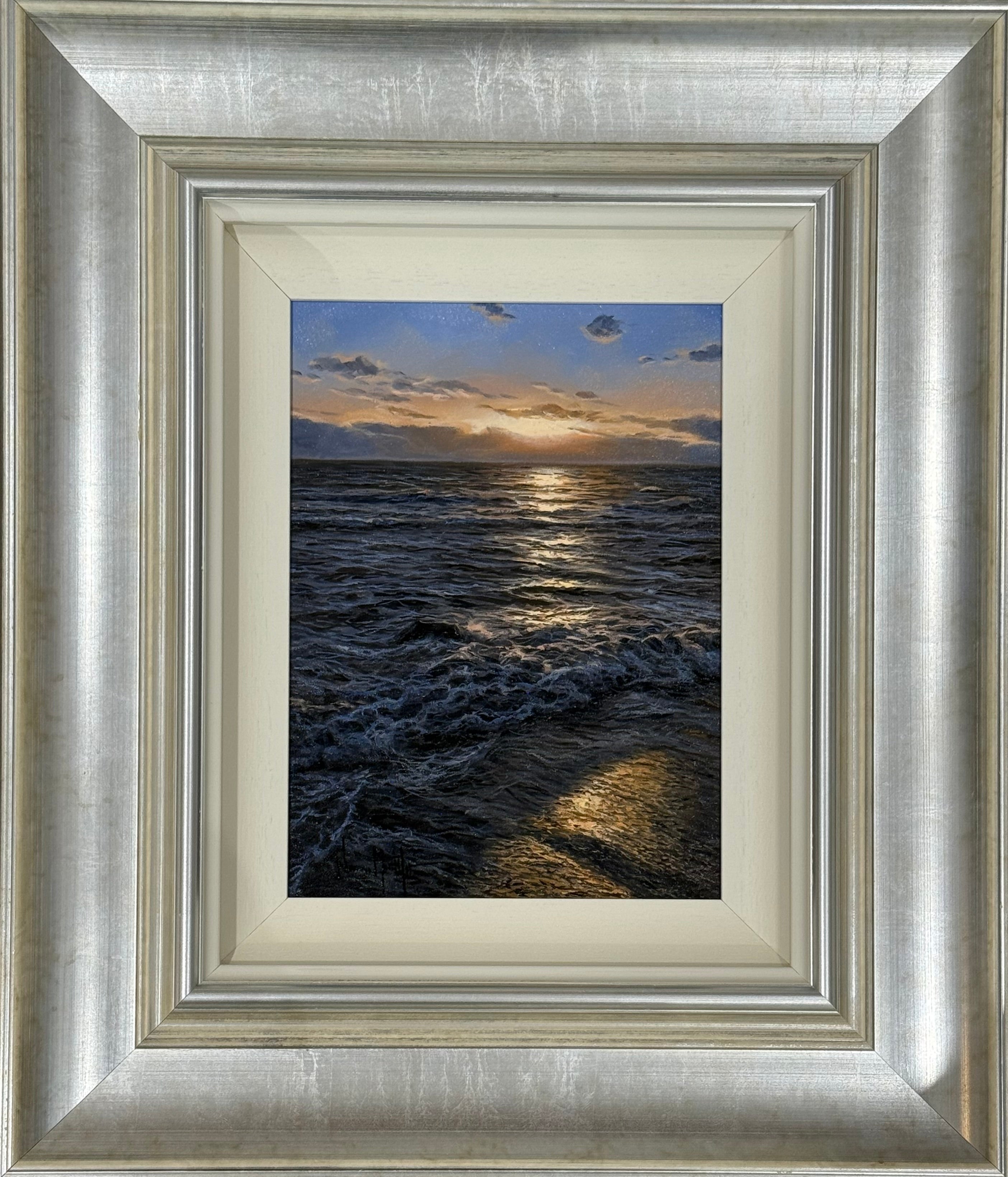 Framed artwork of a sunset over water with a silver frame.