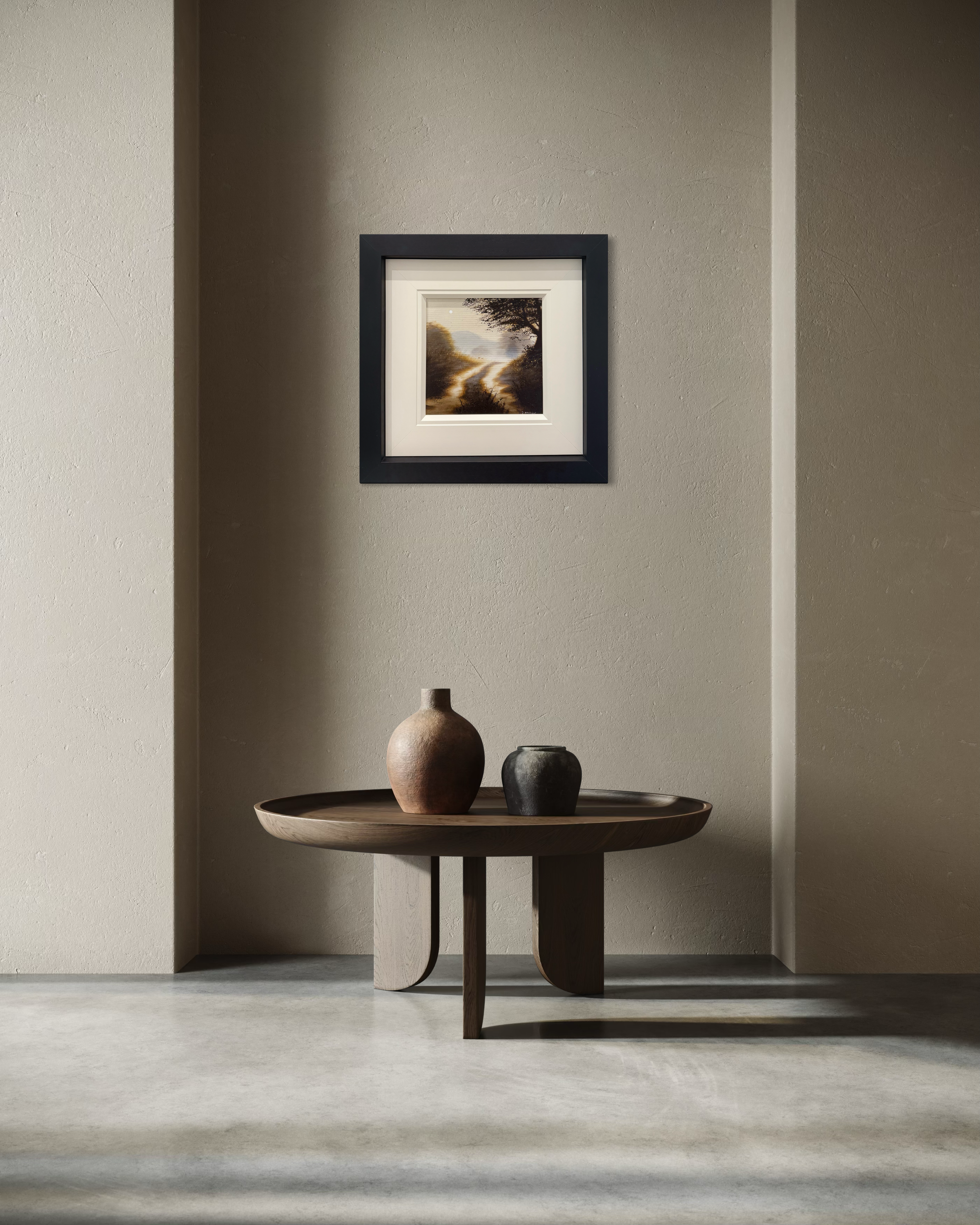 Minimalist interior with a small round table against a wall featuring a framed D J Warilow.