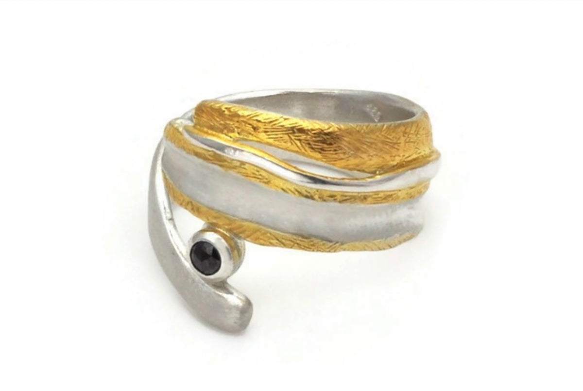 Silver and gold ring with a black gemstone on a white background