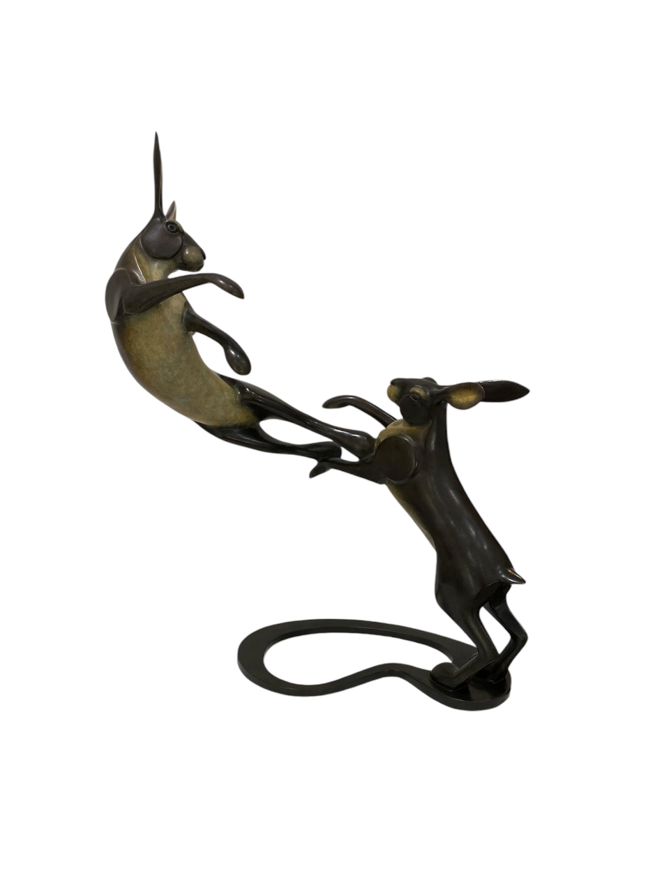 Decorative bronze sculpture of hares boxing on a white background
