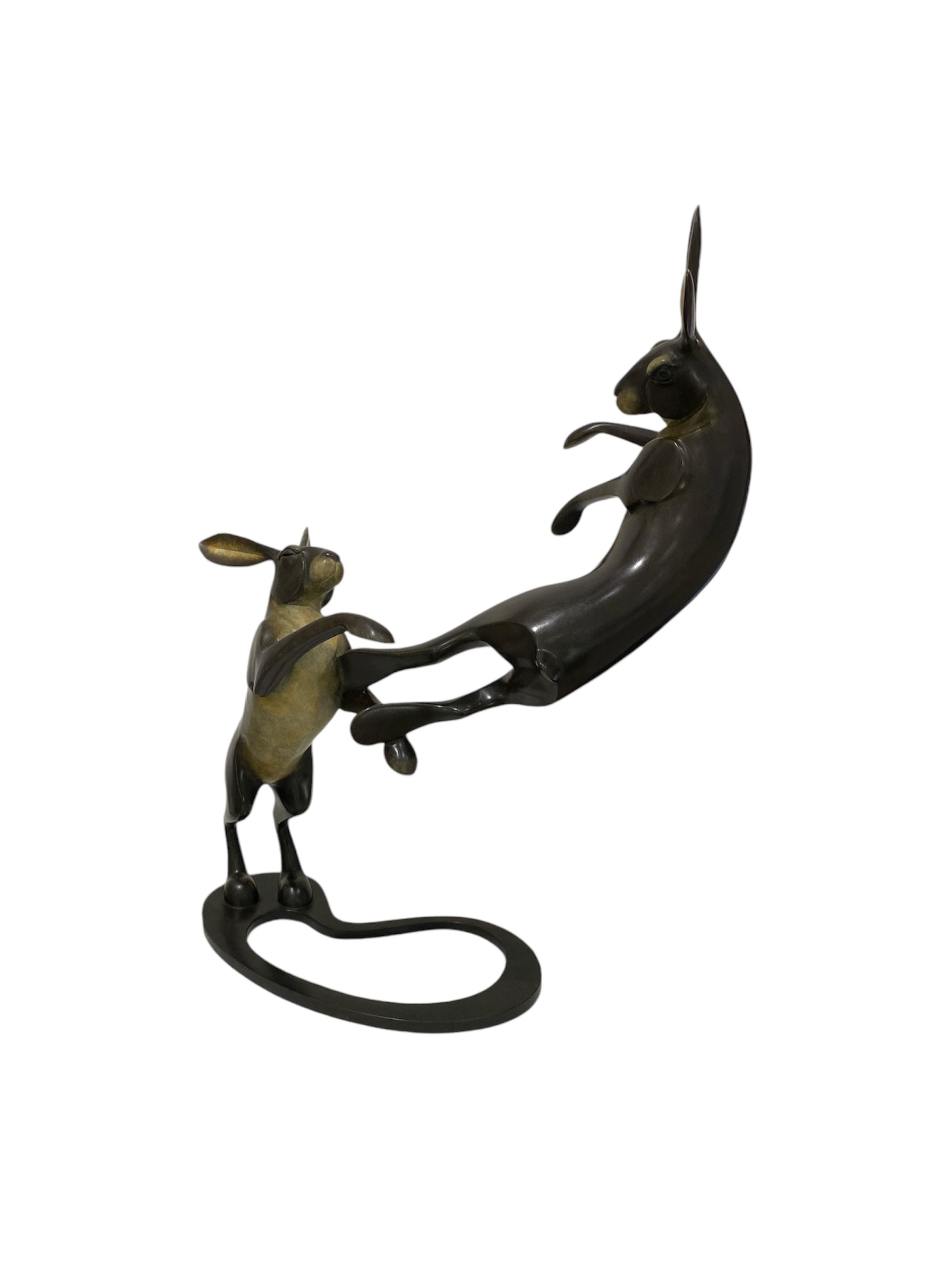 Bronze sculpture of hares fighting on a white background