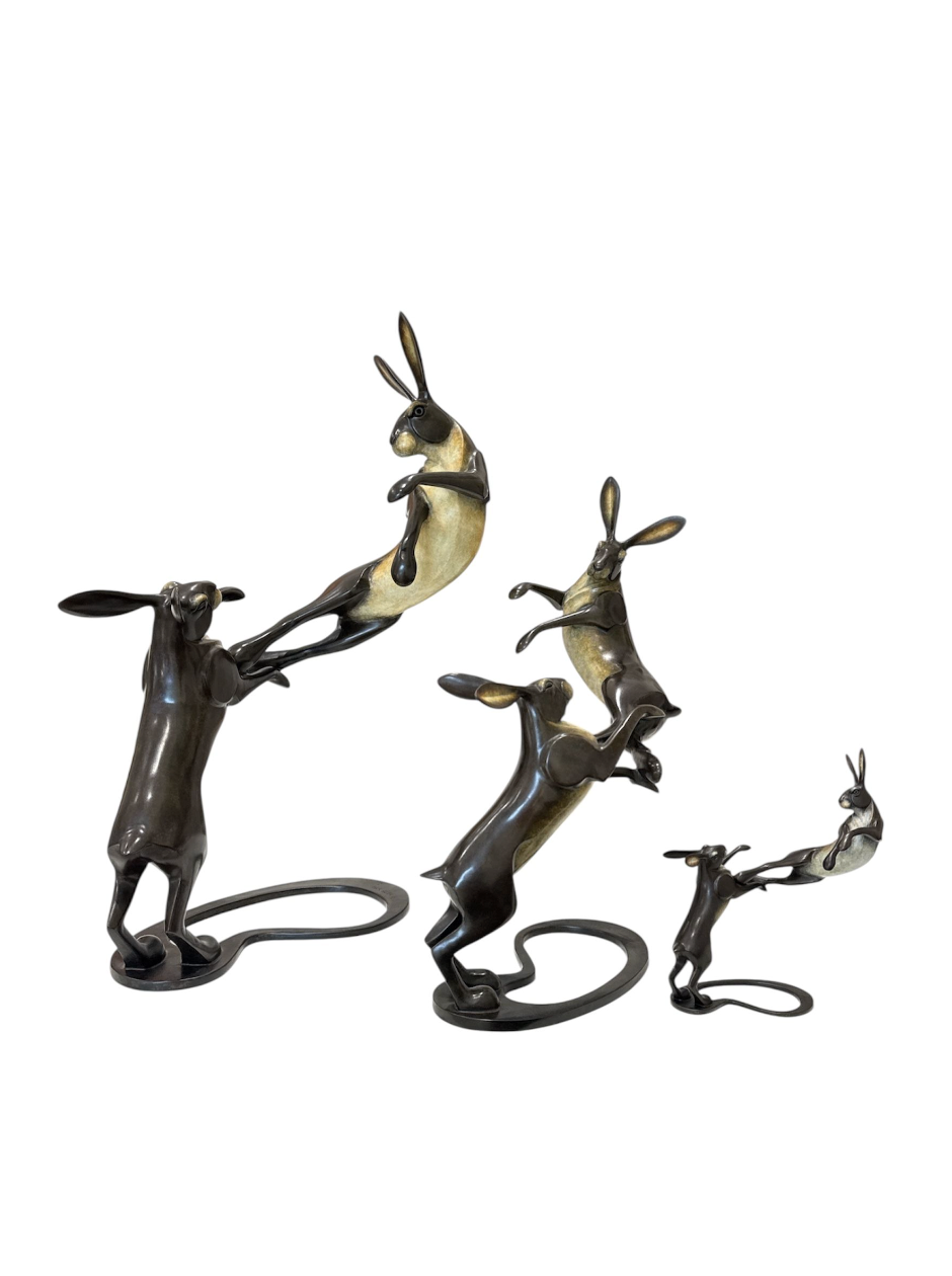 Set of three bronze rabbit sculptures on a white background