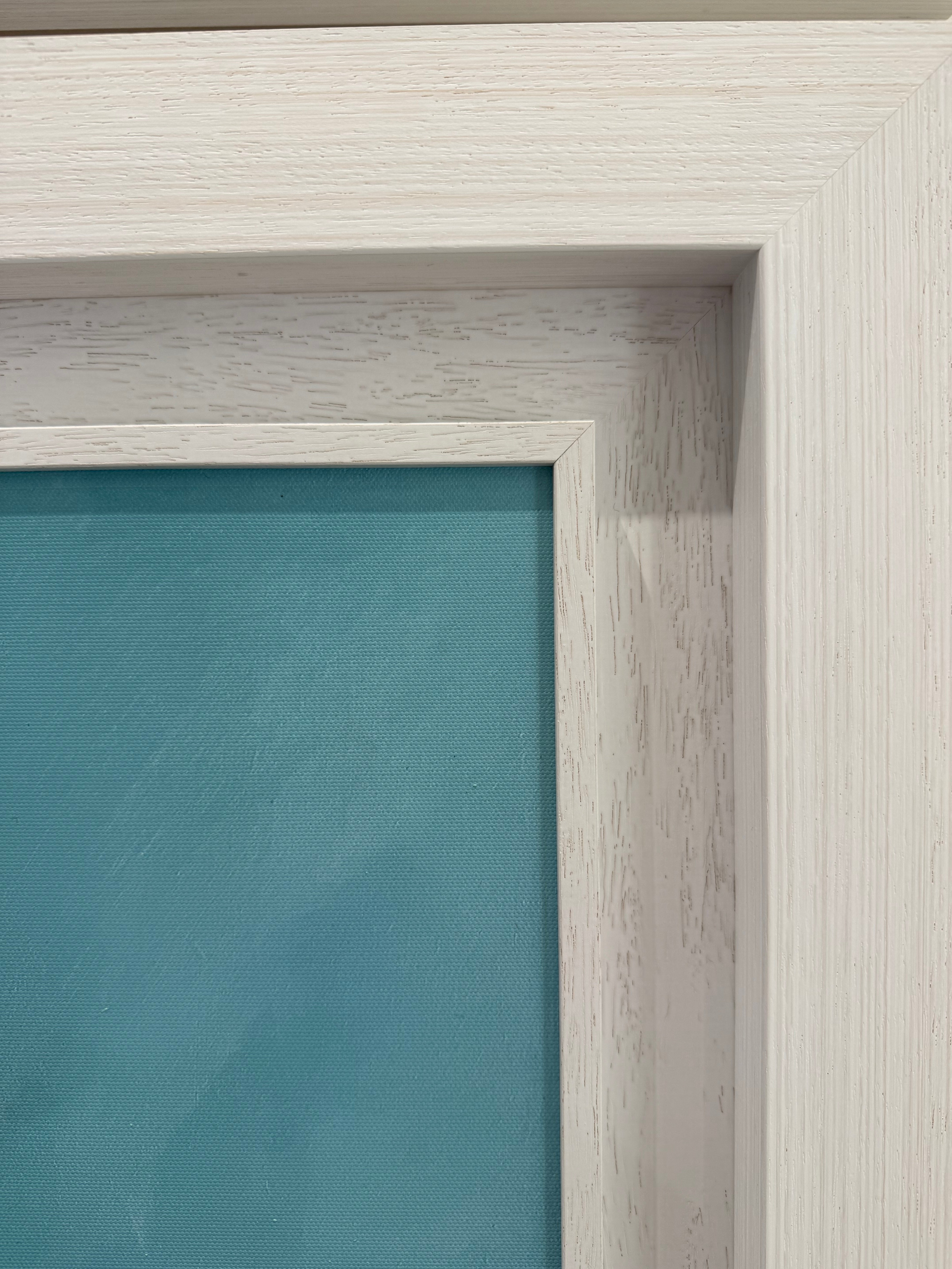 Close-up of a wooden picture frame with a teal canvas inside.