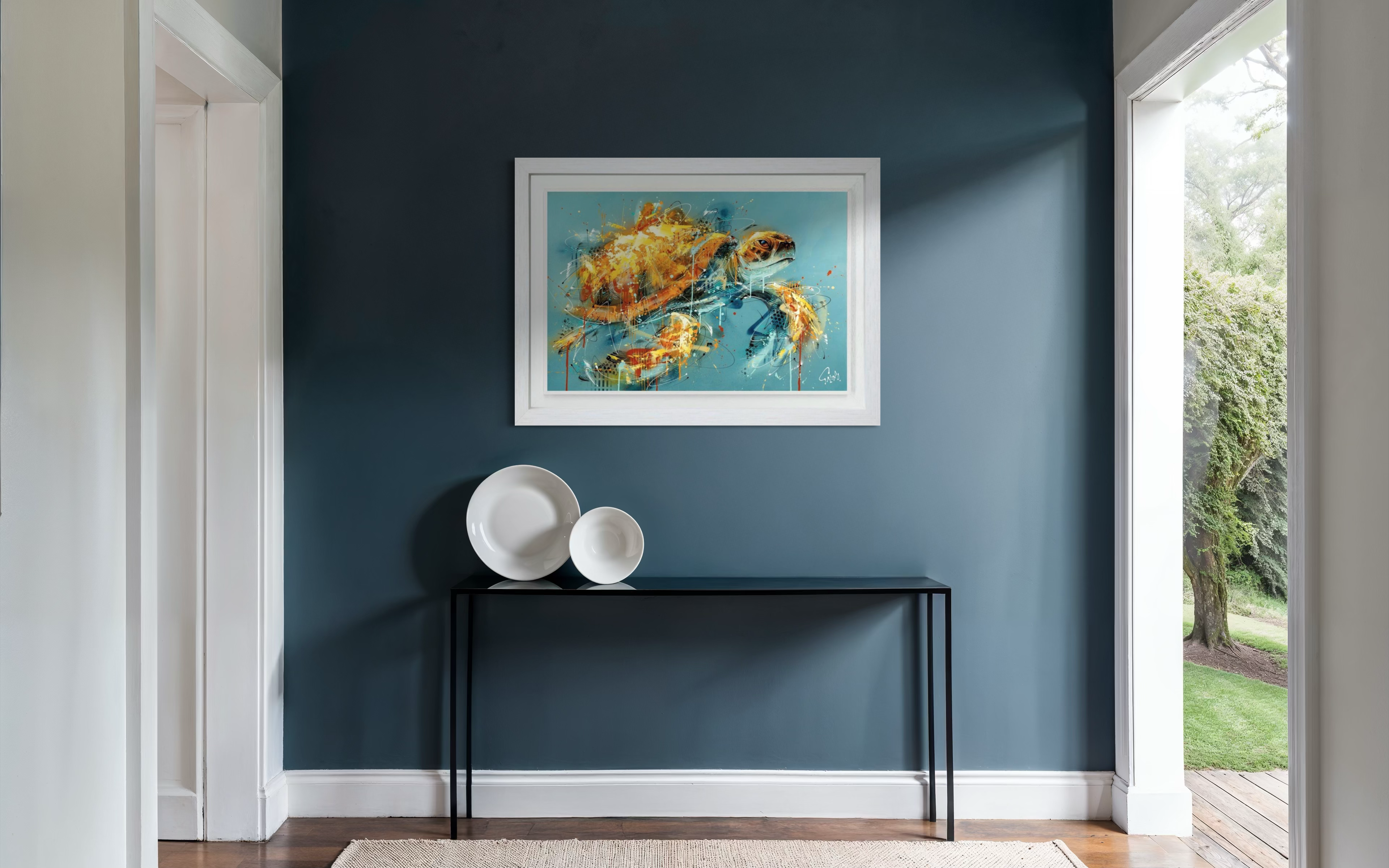 Framed artwork of two crabs on a blue background hanging on a blue wall above a black console table with white plates.