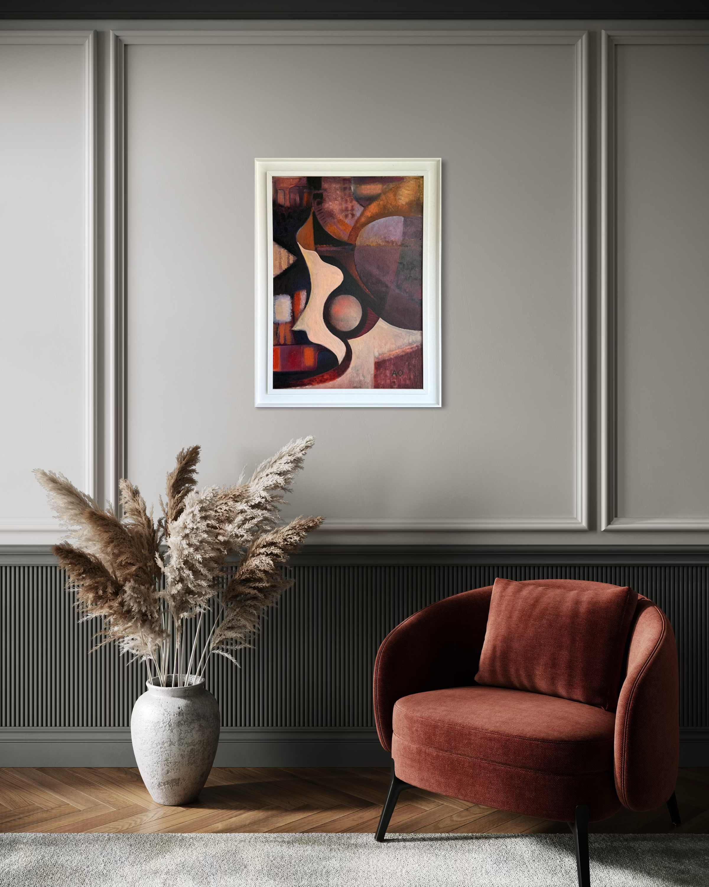 Framed abstract art on a wall above a red armchair and vase with dried plants.