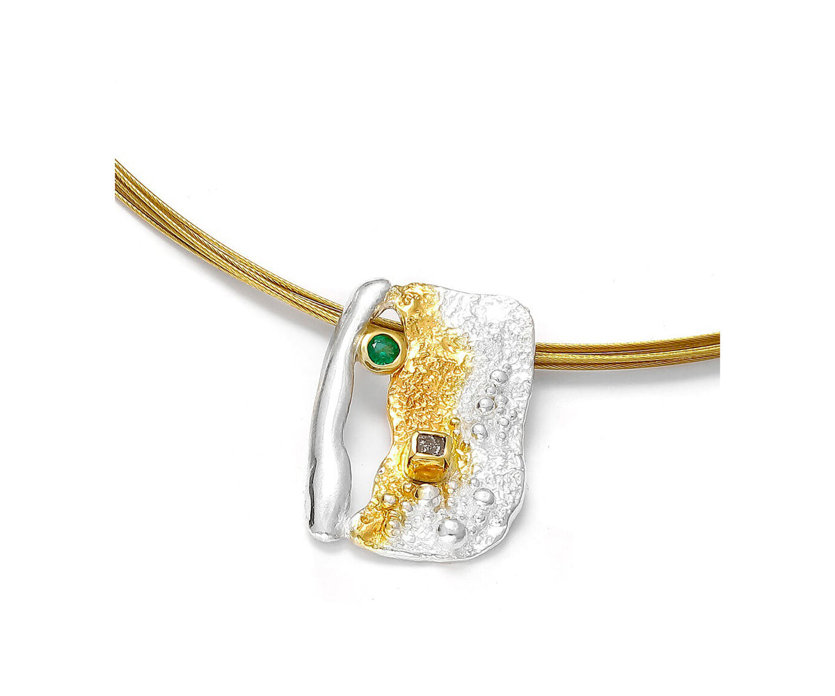 Gold and silver pendant with green gemstone on a white background