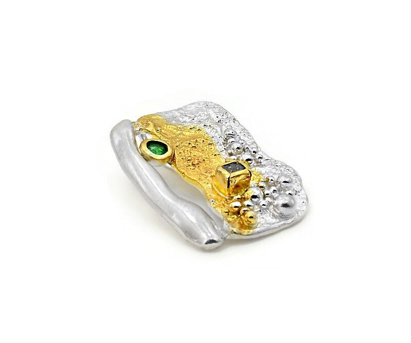 Gold and silver pendant with gemstones on a white background