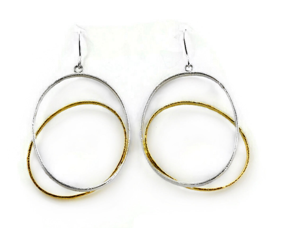 two oval hoops one silver one gold cross over to create a drop earring