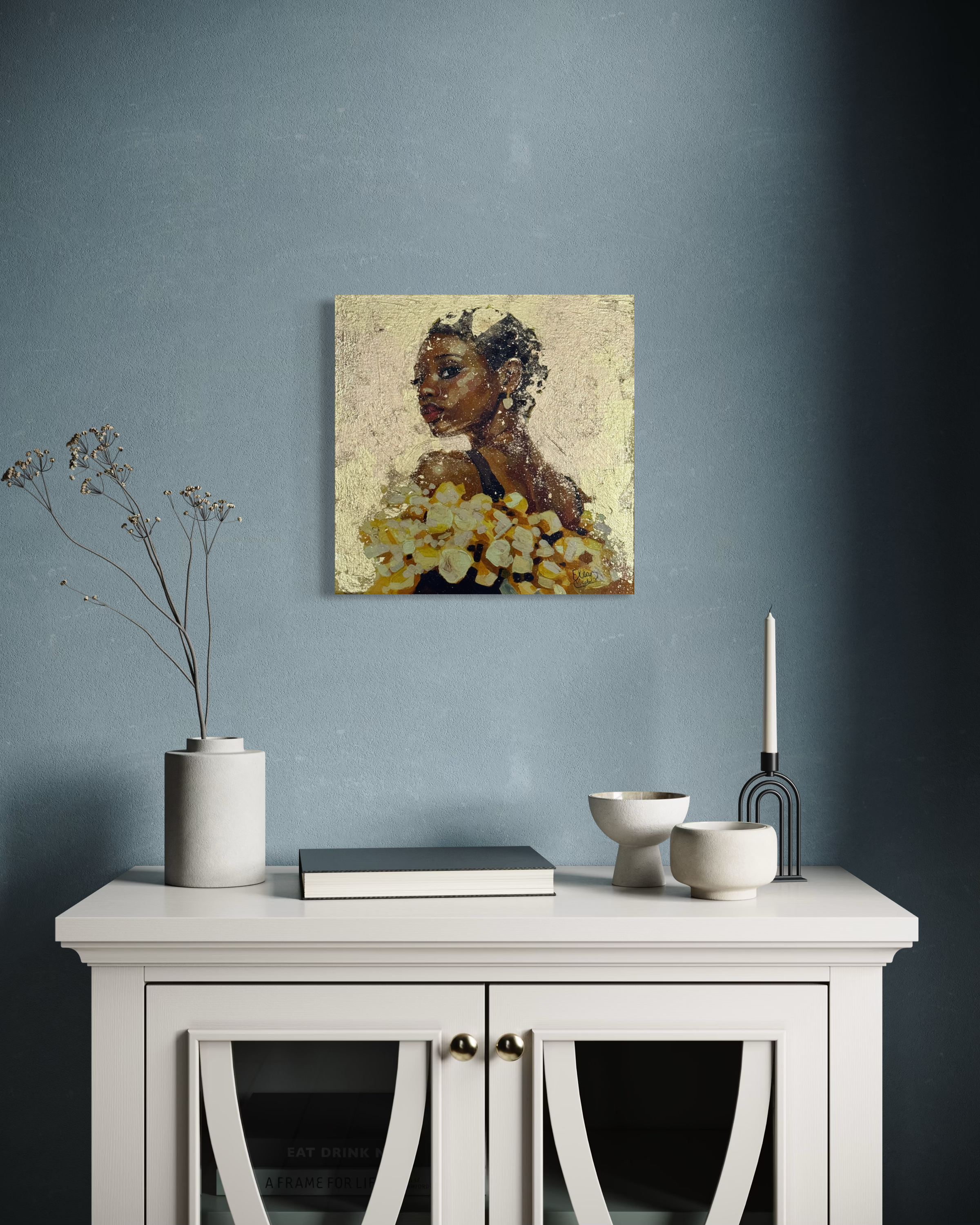 A contemporary original painting with gold leaf detail hanging in a room setting against a blu grey wall above a white chest  of draws