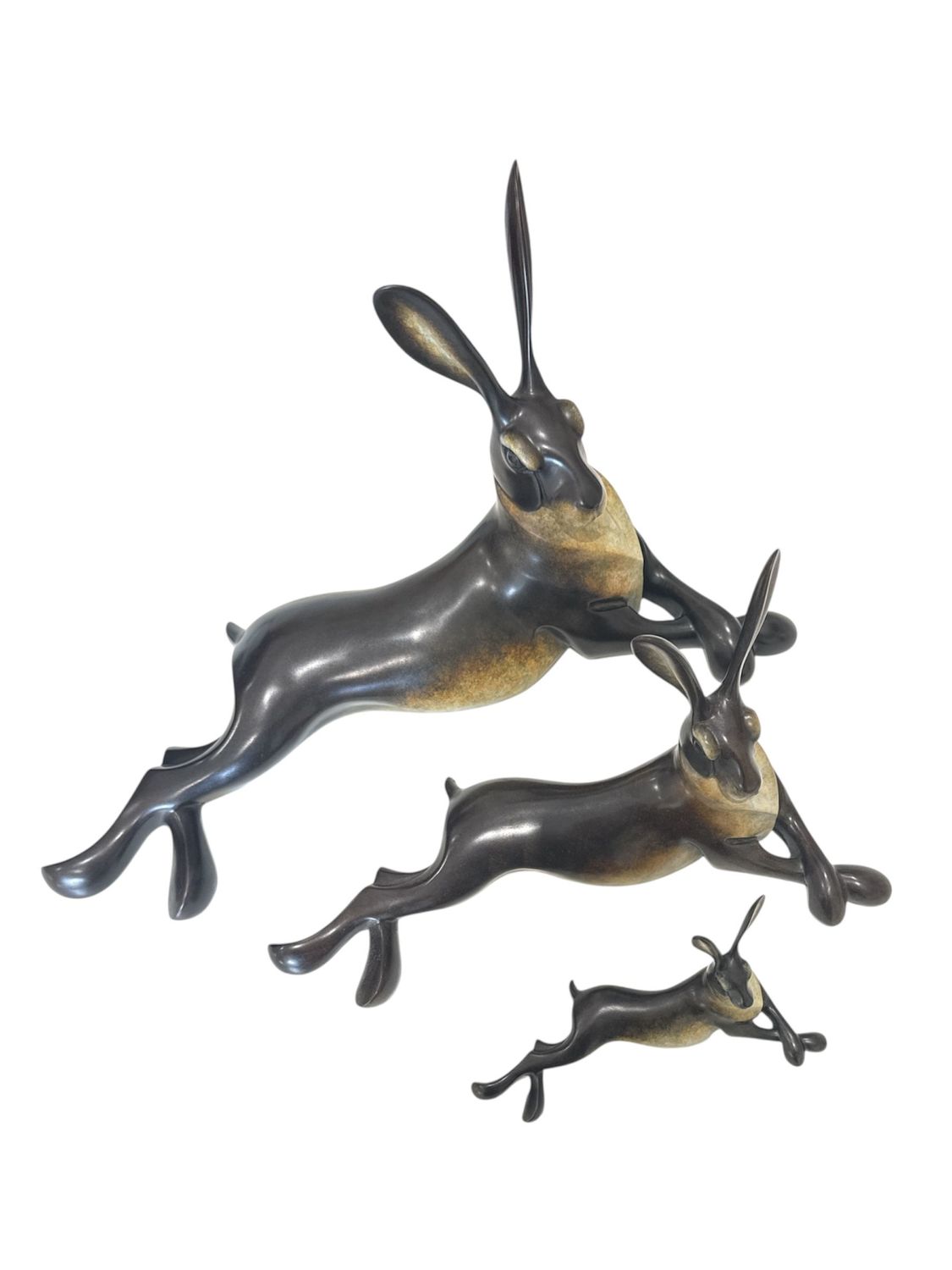 Bronze sculpture of three lying hares on a white background