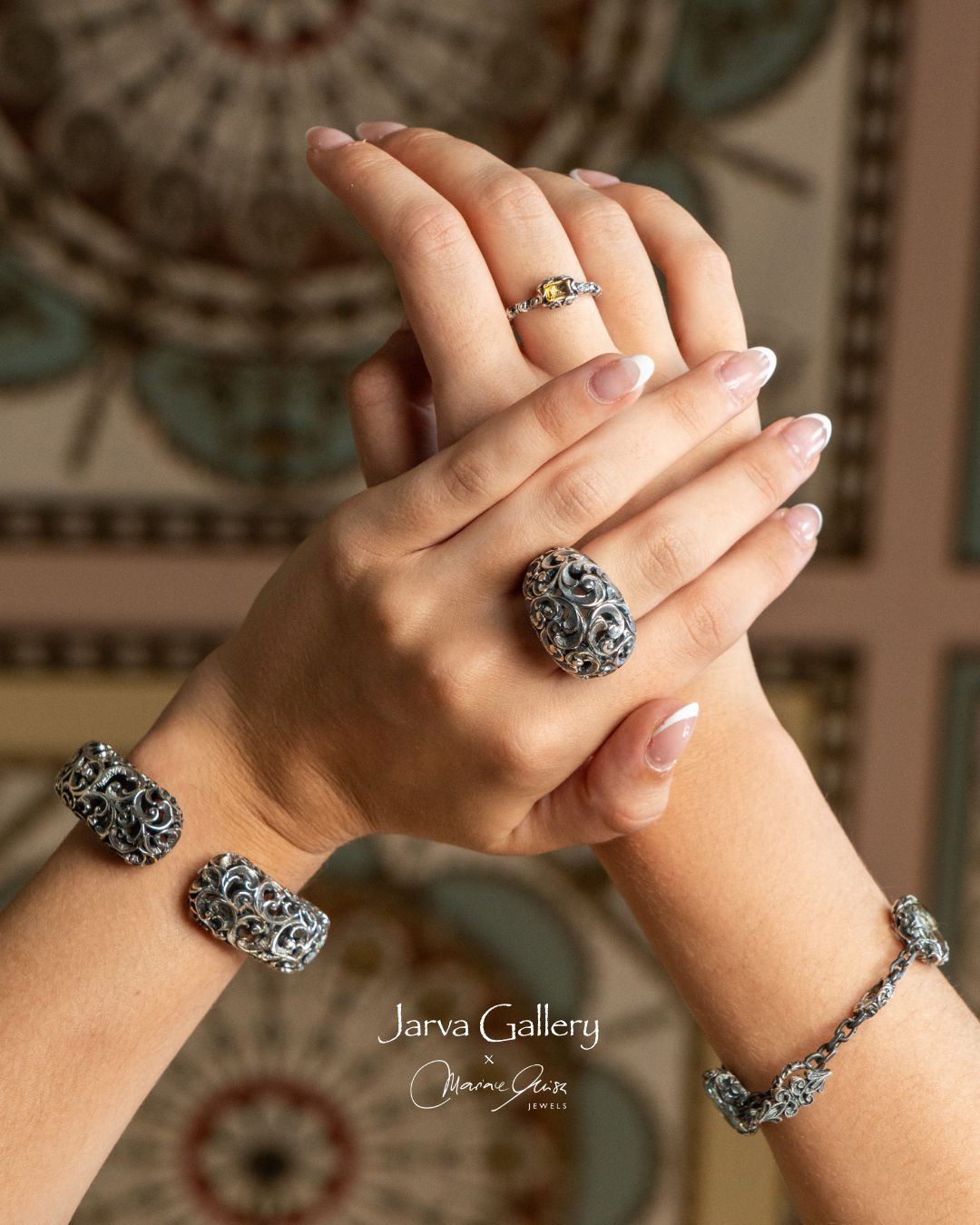 Close-up of hands wearing silver jewelry with a decorative background