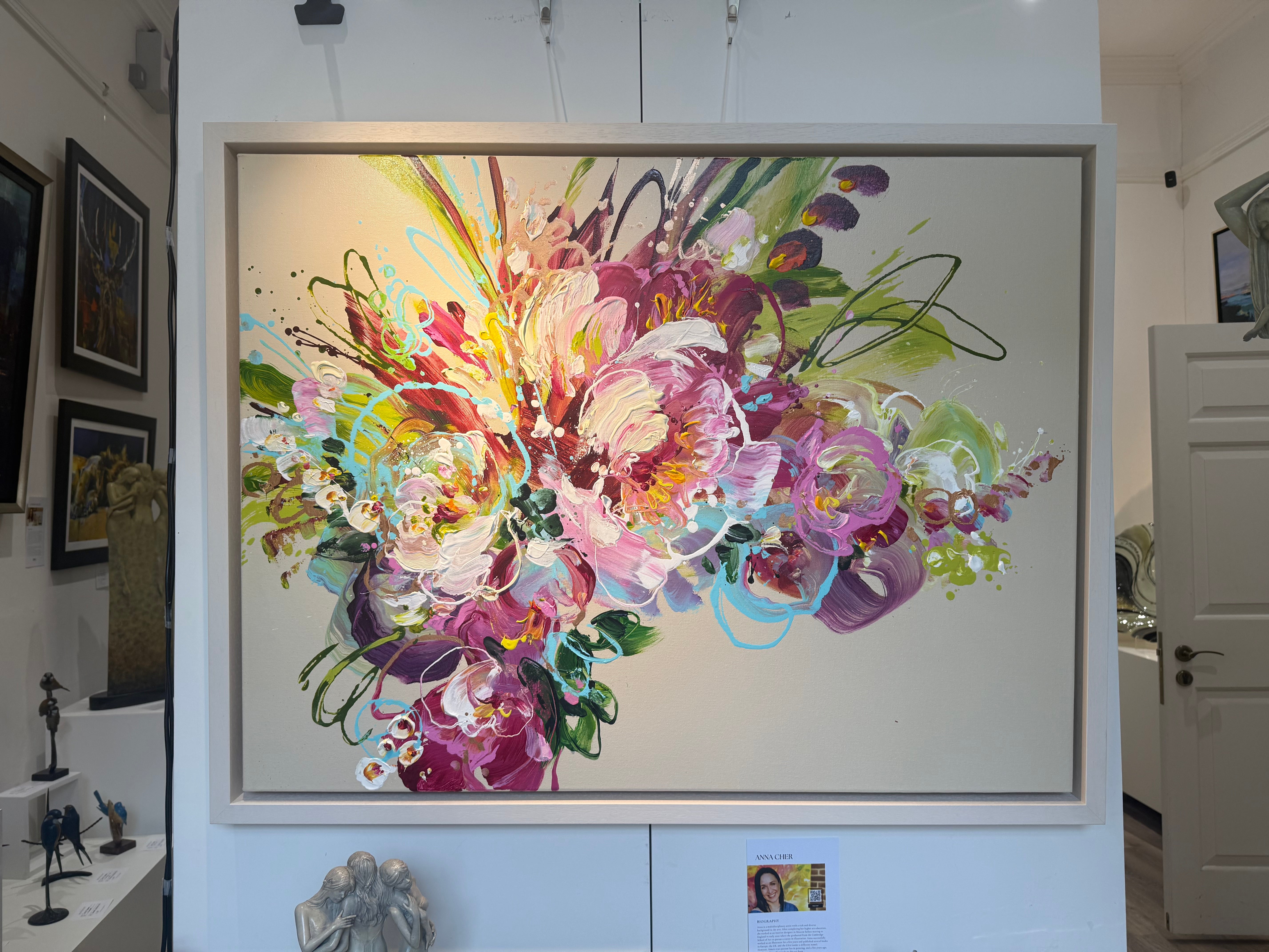 Colorful abstract floral painting in a frame on a wall.